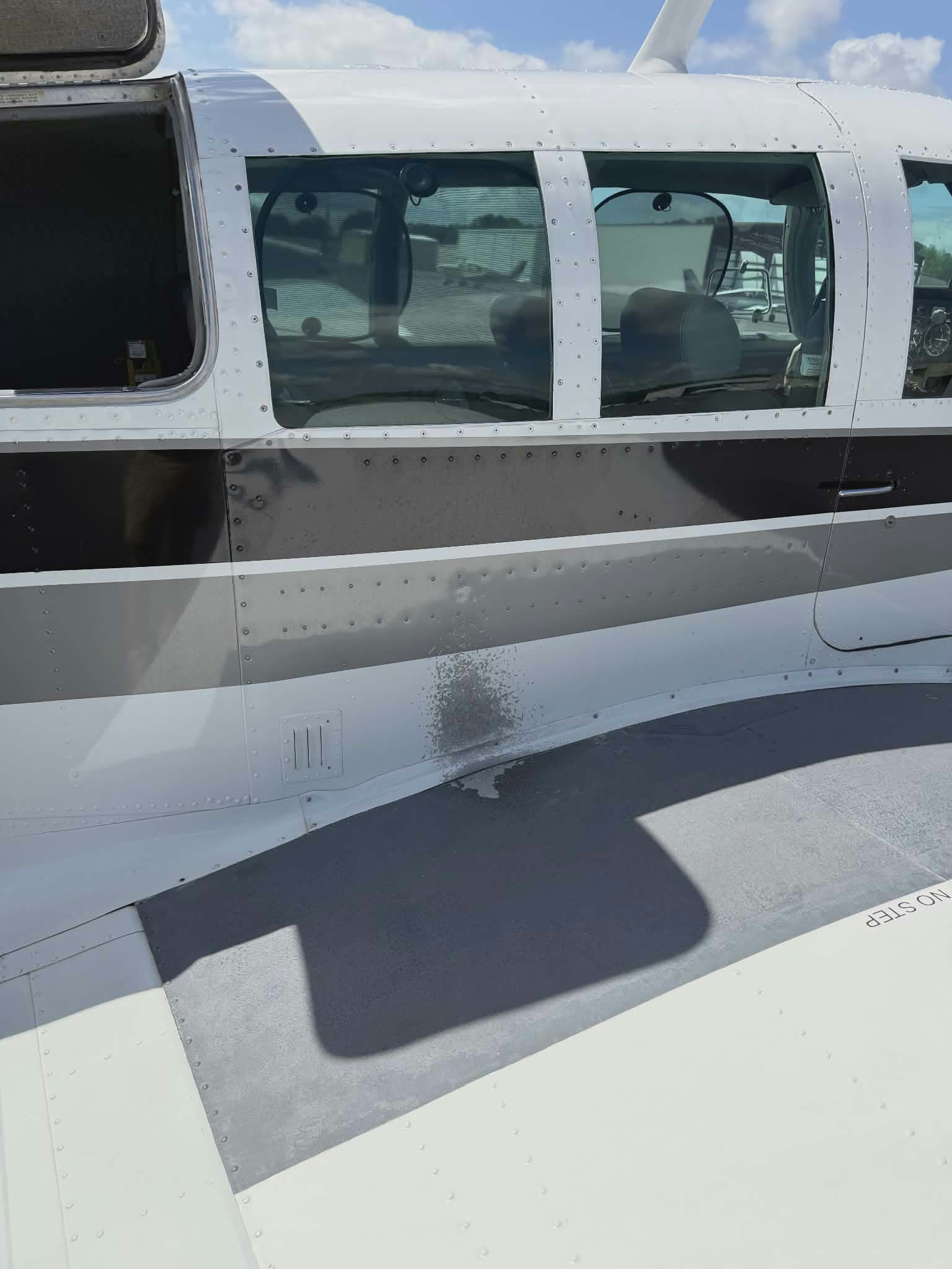 Aircraft fuselage before, with scuffed stripes and surface damage
